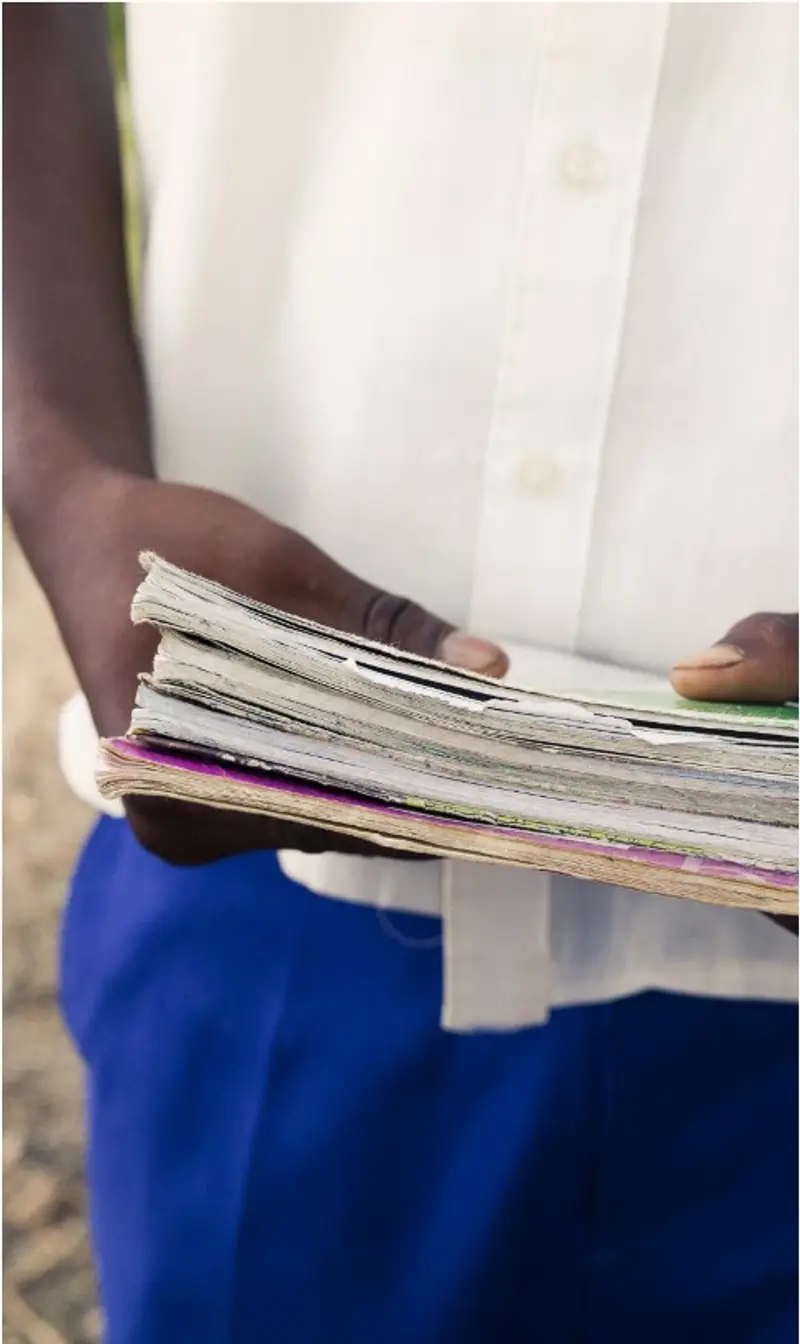 A student holding a stack of worn, dog-eared textbooks